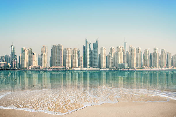 Dubai's skyline with numerous high-rise buildings under construction reflected in calm water.