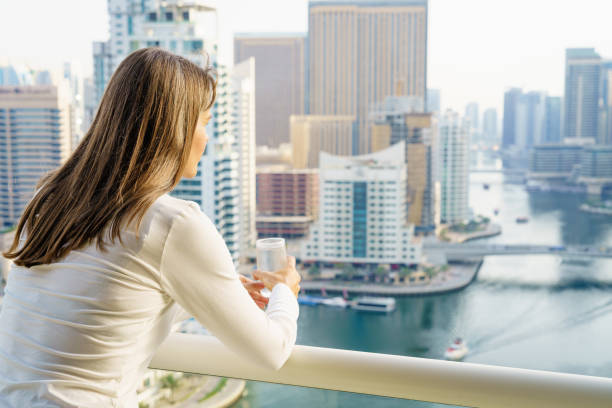 Woman gazing at Dubai skyline from a balcony, representing future potential in off-plan or under construction properties.